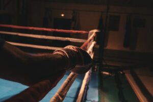 Boxarhandske nära repen i en dunkelt belyst boxningsring